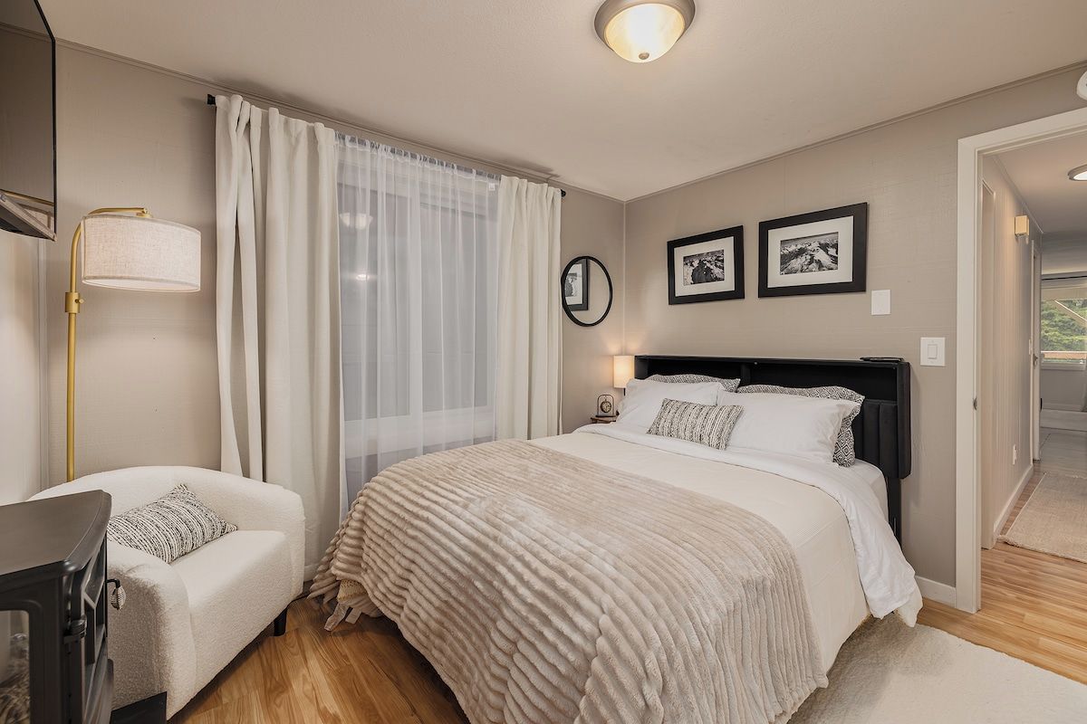 A bedroom with a bed, bedside tables, a lamp, and curtains.