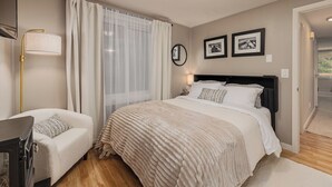 Un dormitorio con cama, mesitas de noche, lámpara y cortinas.