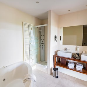A modern bathroom with a bathtub, shower, and a vanity with a mirror and sink. - Hotel Les Dryades Golf & Spa (Pouligny-Notre-Dame)