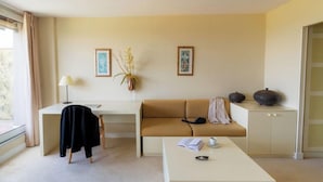 A modern living room with a sofa, a coffee table, a desk, and a lamp. There are two framed pictures on the wall. - Hotel Les Dryades Golf & Spa (Pouligny-Notre-Dame)