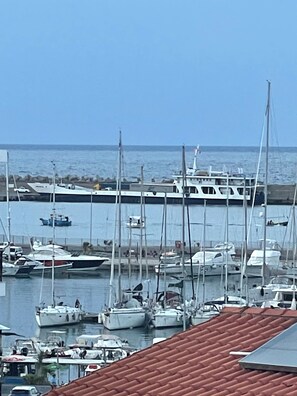 A marina with multiple boats docked, a clear sky, and a calm sea.