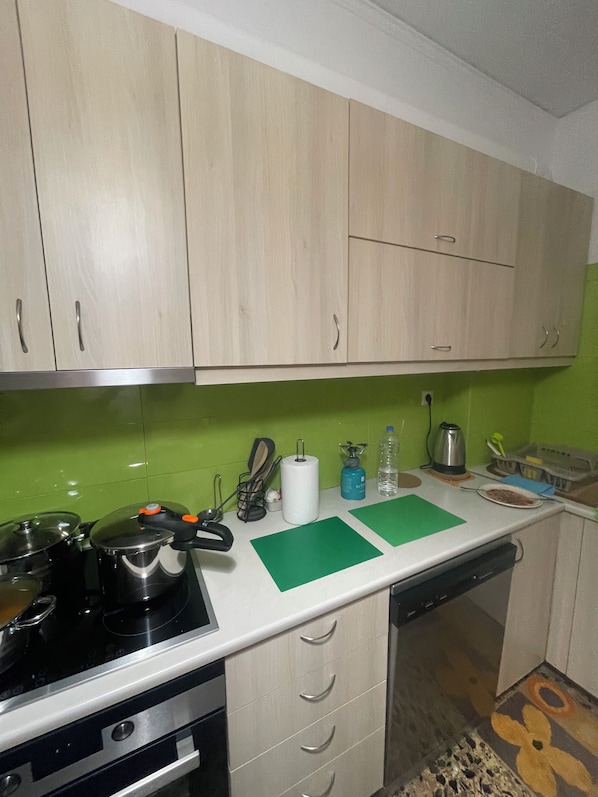 A kitchen with light-colored cabinets, a stove, and a green backsplash.
