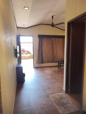 Un pasillo con ventilador de techo, televisor montado en la pared y puerta que da a una habitación.