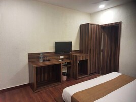 A hotel room with a bed, a desk with a television, and built-in wardrobes.