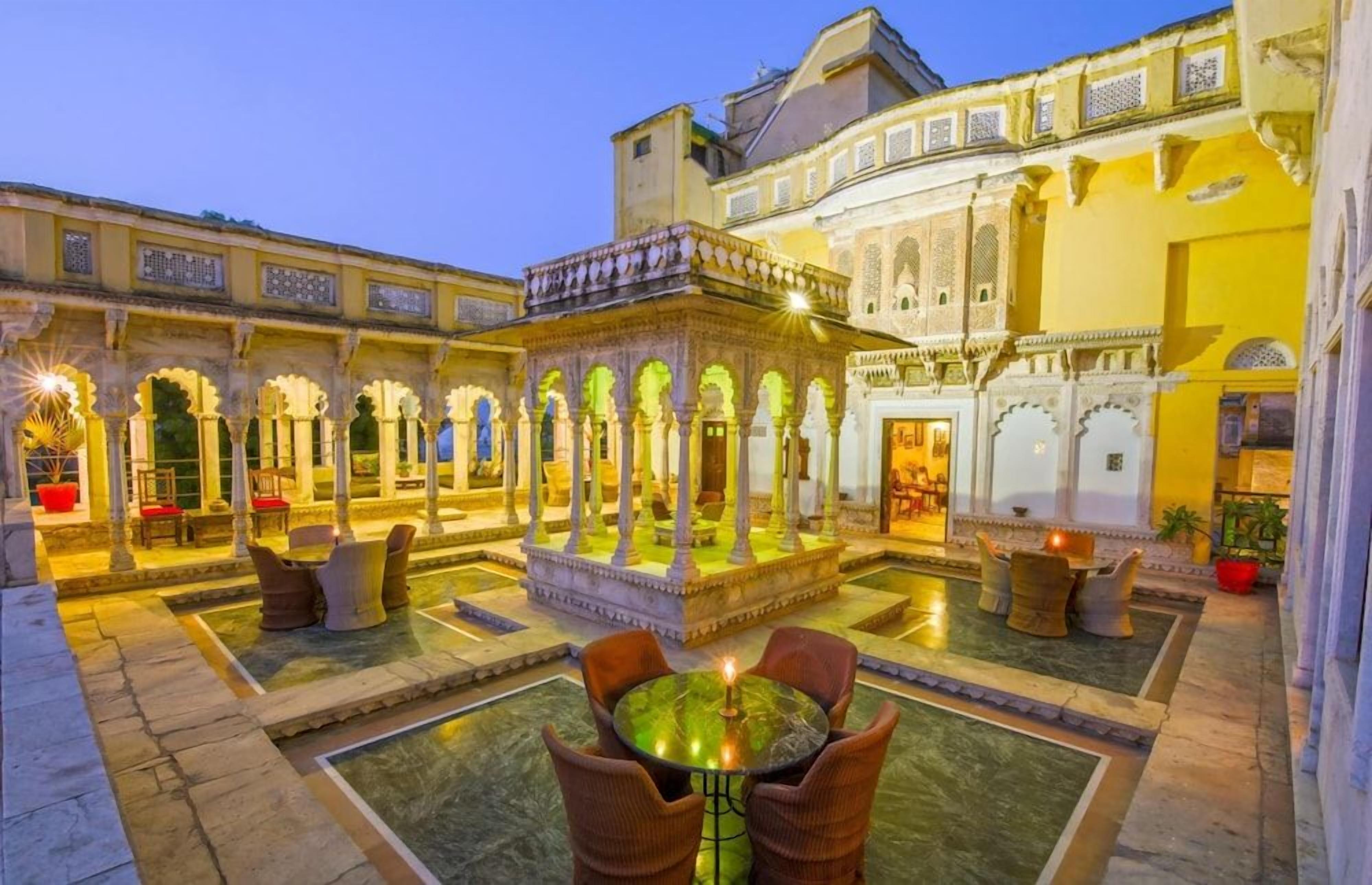 Un patio con una fuente central, zonas de estar y arquitectura ornamentada.