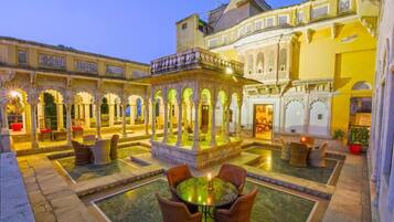 Un patio con una fuente central, zonas de estar y arquitectura ornamentada.