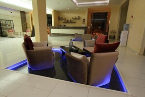 A modern lobby with a reception desk, seating area, and a water dispenser.