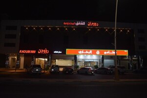 Un edificio con varias fachadas comerciales, incluyendo un hotel llamado RAOUIM INN y una gasolinera.
