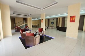 A spacious lobby with a central seating area, a staircase, and a reception desk.