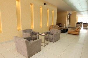 A modern lobby with sofas and a coffee table, a reception desk, and a wall with vertical light panels.
