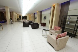 A spacious lobby with a high ceiling, modern furniture, and a central seating area.