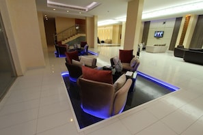 A modern lobby with a reception desk, seating area, and a staircase. - Raoum Inn Serviced Apartments Khafji (Al Khafji)