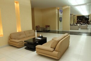 Um lobby moderno com um conjunto de sofás, uma mesa de centro e uma televisão de tela plana na parede.