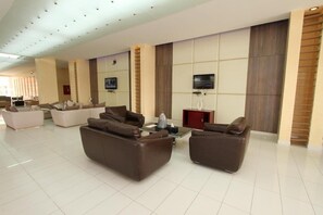 A spacious living area with sofas and a coffee table, a flat-screen TV mounted on the wall, and a red cabinet.