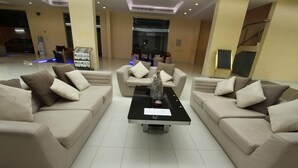 Una hall con tre divani, un tavolino da caffè e un banco reception.