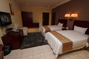 Habitación de hotel con dos camas, un escritorio, un televisor y una puerta.