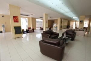 A spacious lobby with a high ceiling, a staircase, and leather sofas.
