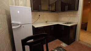 Una cucina compatta con mobili scuri, un frigorifero bianco e un lavello.