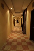 Un pasillo de hotel con suelo de cuadros, puertas a ambos lados e iluminación empotrada.