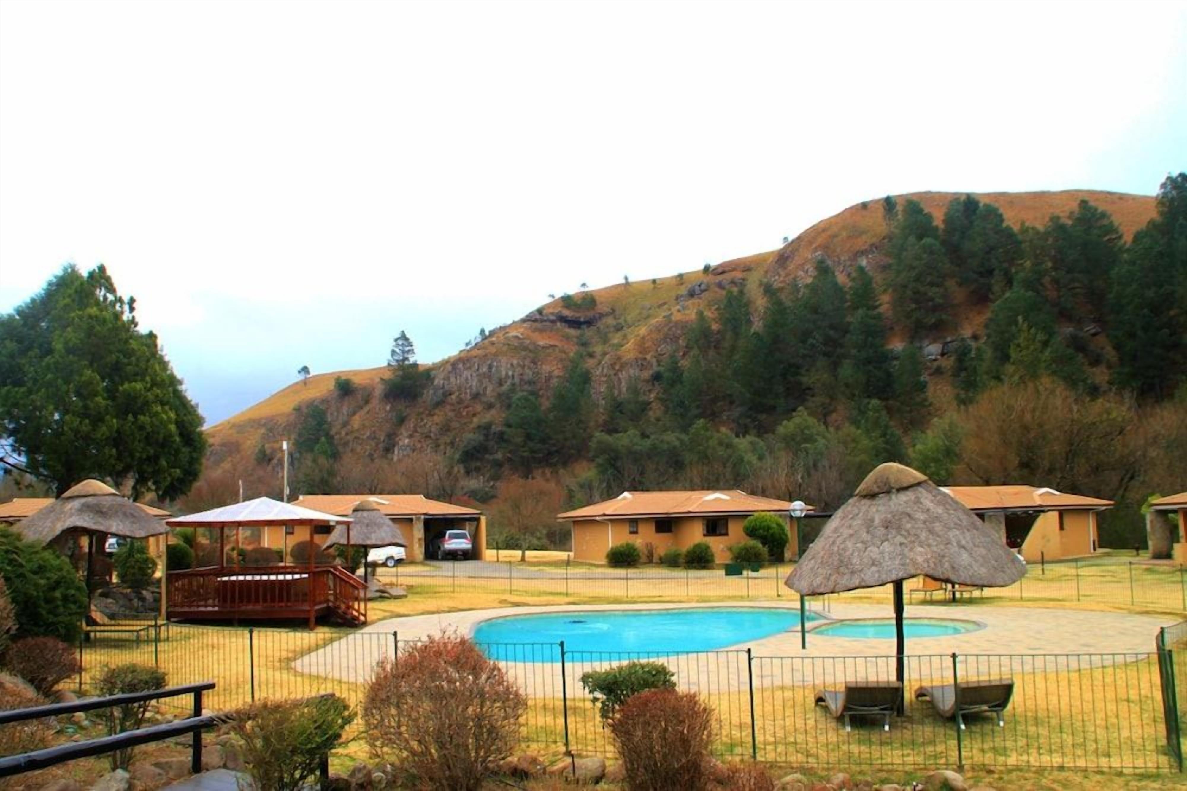 Un complexe hôtelier doté d’une piscine, de bâtiments à toits de chaume et situé dans un cadre vallonné.