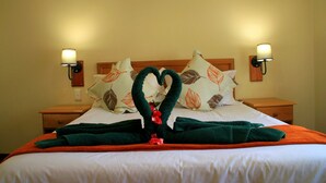 Una camera d'albergo con un letto rifatto, due comodini e lampade a parete.