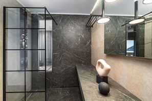 A modern bathroom with a glass shower enclosure, a marble-tiled wall, and a large mirror. - San Giovanni Luxury Studios (Lefkada)