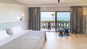 A hotel room with a large bed, a balcony with a table and chairs, and a view of the sea. - San Giovanni Luxury Studios (Lefkada)