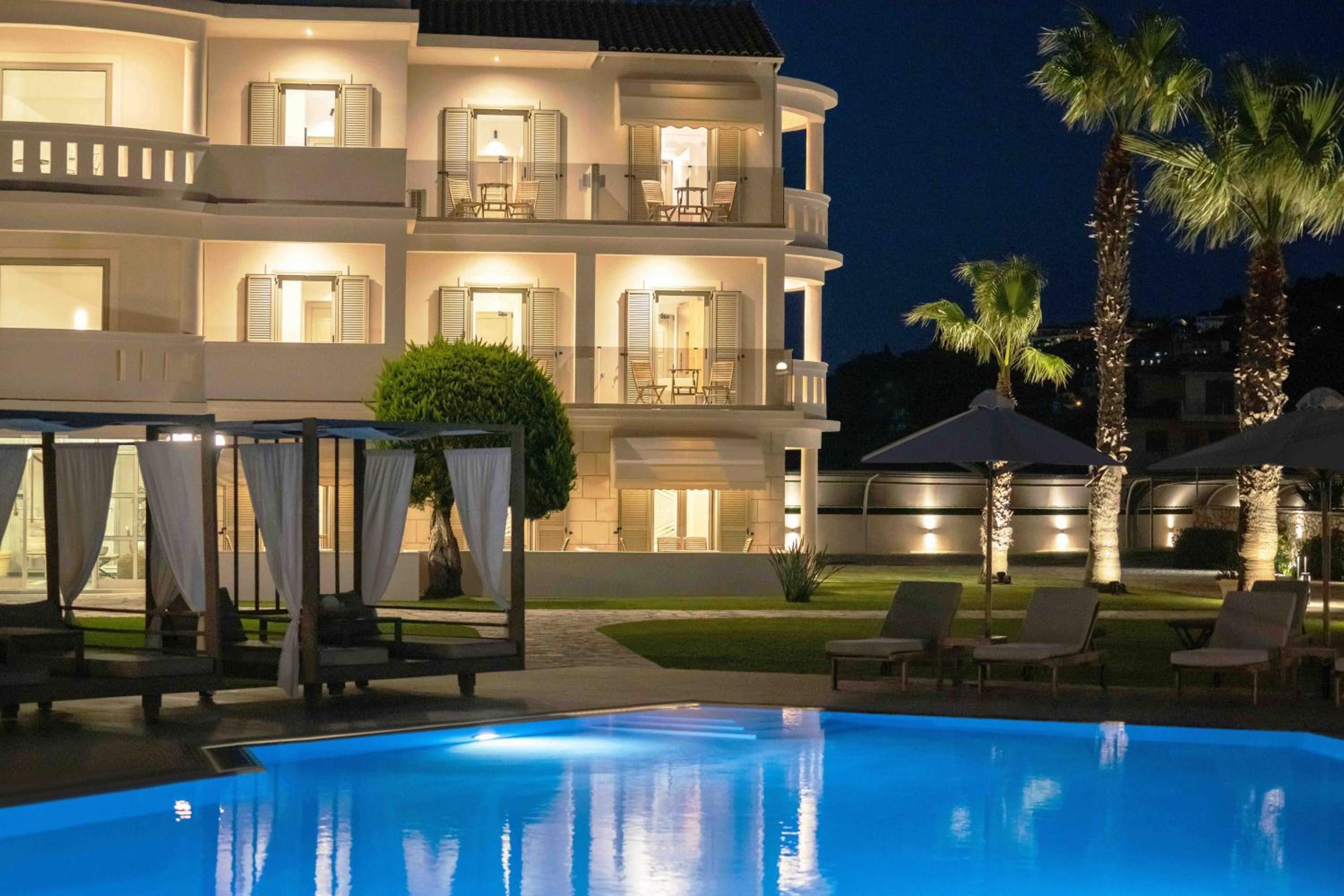 Un hotel de varios pisos con balcones, piscina y mobiliario exterior.