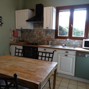 A kitchen with white cabinets, a black range hood, a window with a view, a sink, and a microwave. - Le Clos Gentiane [vr] (Saint-Etienne)