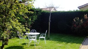 A well-maintained grassy area with a metal table and chairs, a tree, and a hedge. - Le Clos Gentiane [vr] (Saint-Etienne)