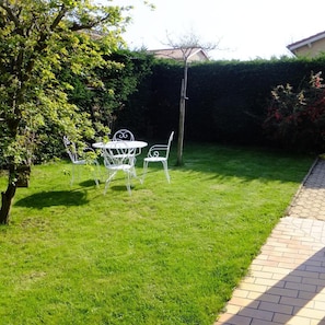 A well-maintained grassy area with a metal table and chairs, a tree, and a hedge. - Le Clos Gentiane [vr] (Saint-Etienne)