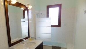 A bathroom with a large mirror, a sink, a bathtub, and a window. - Le Clos Gentiane [vr] (Saint-Etienne)