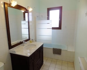 A bathroom with a large mirror, a sink, a bathtub, and a window. - Le Clos Gentiane [vr] (Saint-Etienne)