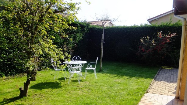 A well-maintained garden with a lawn, a patio area, and a metal table and chairs. - Le Clos Gentiane [vr] (Saint-Etienne)
