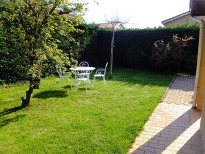 A well-maintained garden with a lawn, a patio area, and a metal table and chairs. - Le Clos Gentiane [vr] (Saint-Etienne)