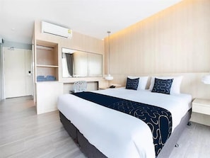 Una habitación de hotel con una cama grande, un armario, un espejo y una mesita de noche.