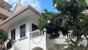 Um edifício de dois andares com varanda coberta, área de estar externa e piscina.