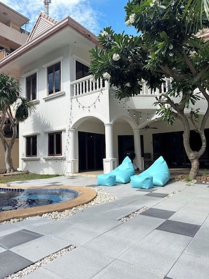 A two-story building with a covered patio area, outdoor seating, and a swimming pool. - Capital O 631 Blooming Hill Boutique Suites (Pattaya)