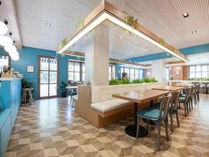 Ein Restaurant mit kariertem Boden, einer zentralen Sitzgruppe mit einer Bank und einer Theke mit Hockern.