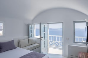 Ein Schlafzimmer mit Bett, einer Couch, einem Fernseher und einem Balkon mit Meerblick.