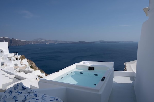 Ein weißer Infinity-Pool mit Whirlpool auf einem Balkon mit Blick auf das Meer.