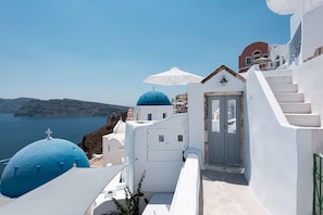 Ein Küstengebäude mit weißen Wänden und blauen Kuppeln, eine Treppe und Blick aufs Meer.