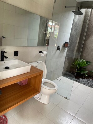 Casa de banho moderna com lavatório branco, sanita e cabine de duche em vidro.