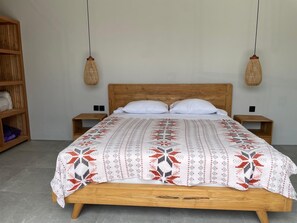 A bed with a patterned bedspread, wooden headboard, two bedside tables, and two hanging lamps. - Rumah Melissa Modern Boho 3BR Villa in Sanur (Denpasar selatan)