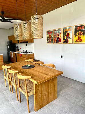 Une cuisine moderne avec des meubles en bois, un réfrigérateur noir et un coin repas comprenant une table et des chaises en bois.