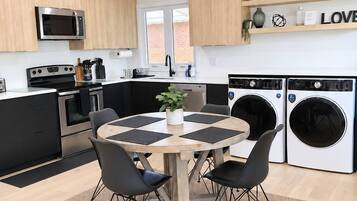 Una cocina moderna con una isla central, electrodomésticos integrados y un comedor con una mesa redonda y sillas.