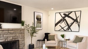 Una sala de estar moderna con chimenea, un televisor de pantalla plana, una mesa de centro y dos sillones.