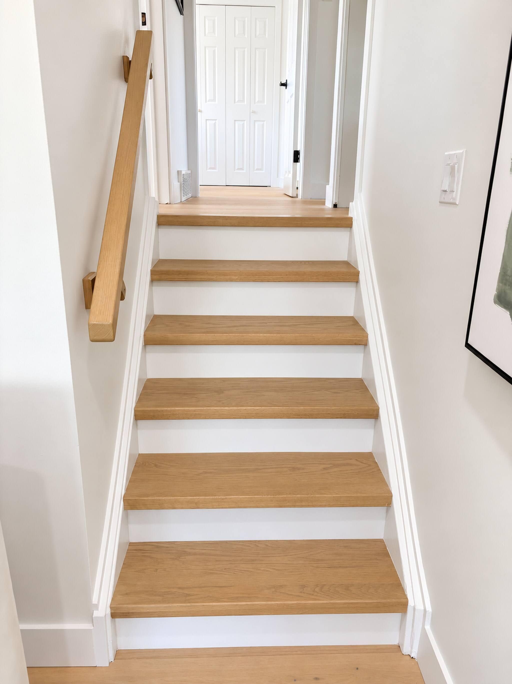 Una escalera con escalones de madera y paredes blancas.