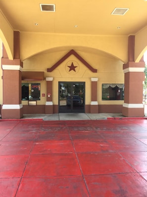 A building entrance with a star logo, a red tiled floor, and a sign indicating 'OPEN'.