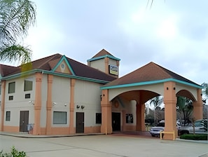 A building with a central entrance, multiple windows, and a covered area with columns.